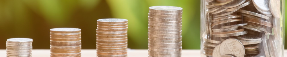 Close-up photo of stacks of coins and a jar filled with coins